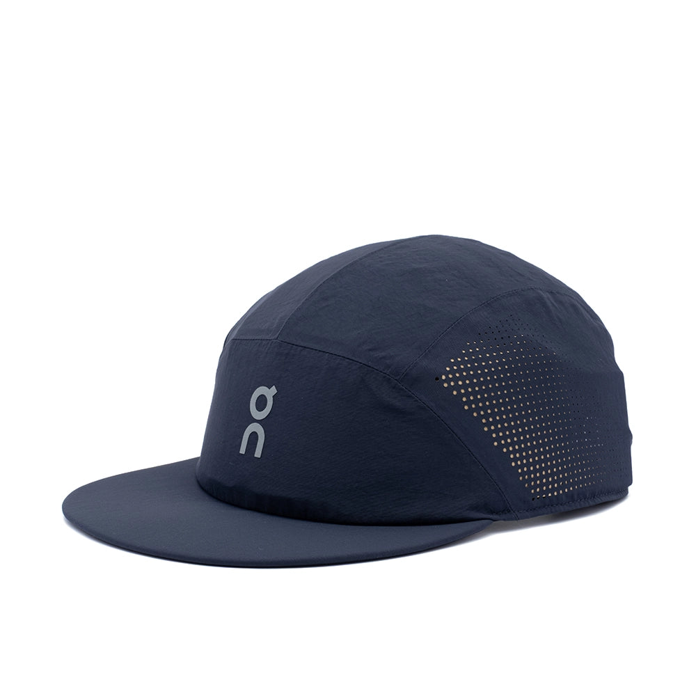 A dark navy blue On running cap with a flat brim, featuring a light gray On logo on the front panel and a perforated side panel, shown against a plain white background.