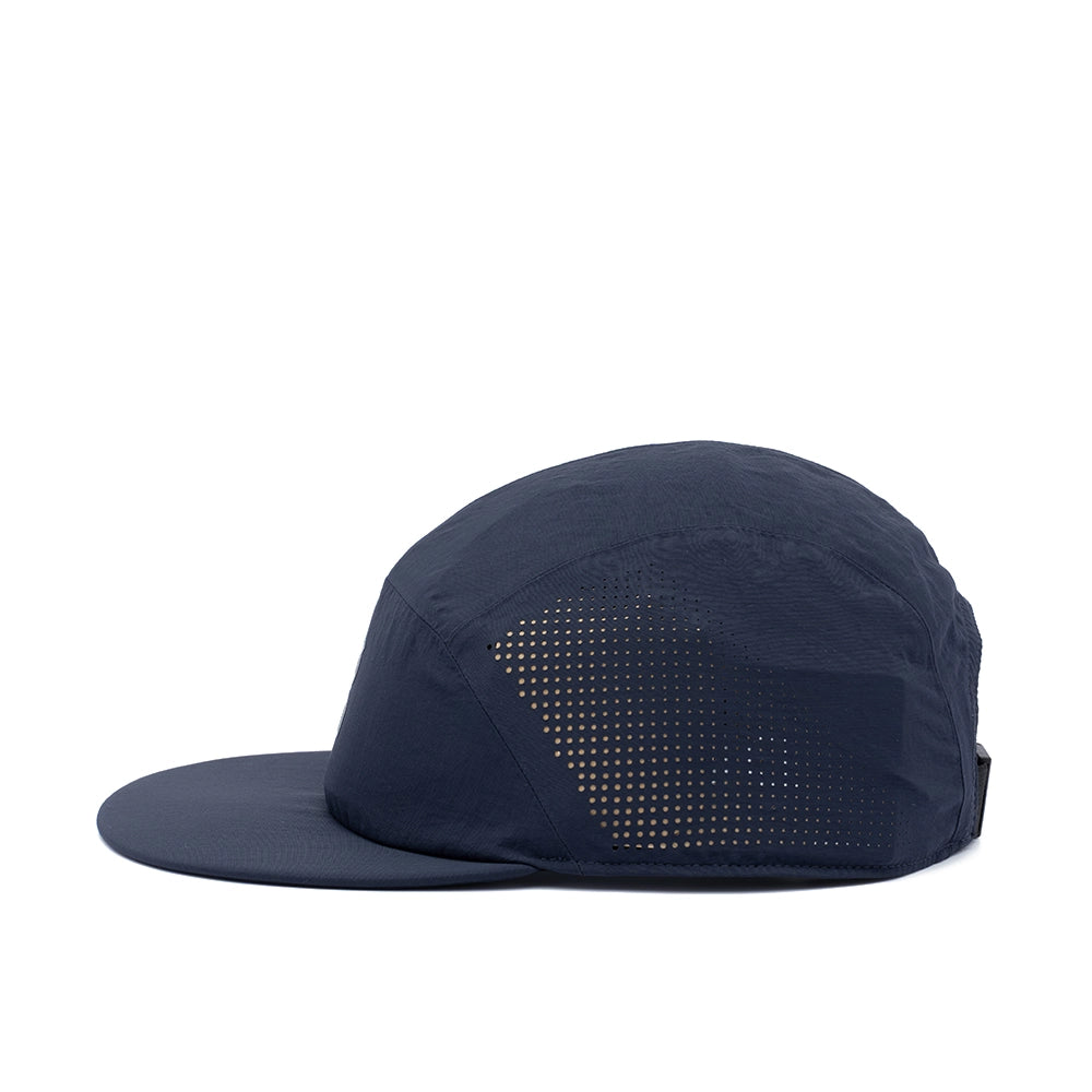 A dark navy blue 5-panel running cap with a flat brim and a triangular pattern of perforated holes on the side, shown from a side profile against a white background.