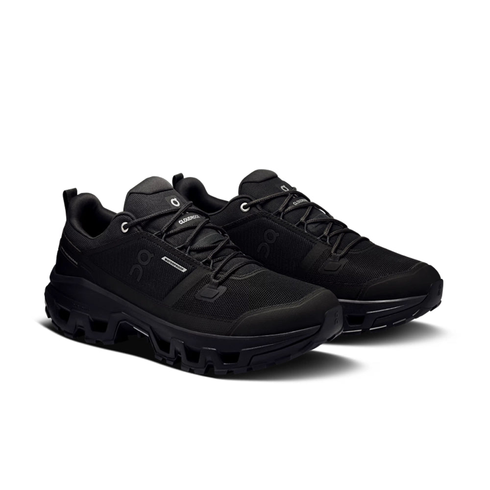 Pair of black On Cloudrock Low Waterproof hiking shoes, angled front view showing the laces and reinforced toes.