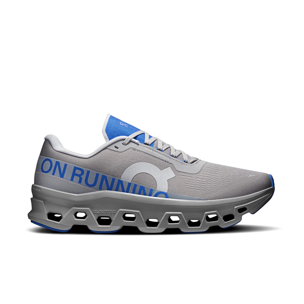 On Cloudmonster 1 Alloy Jay sneaker in gray with blue branding and a sculpted CloudTec sole, side view.