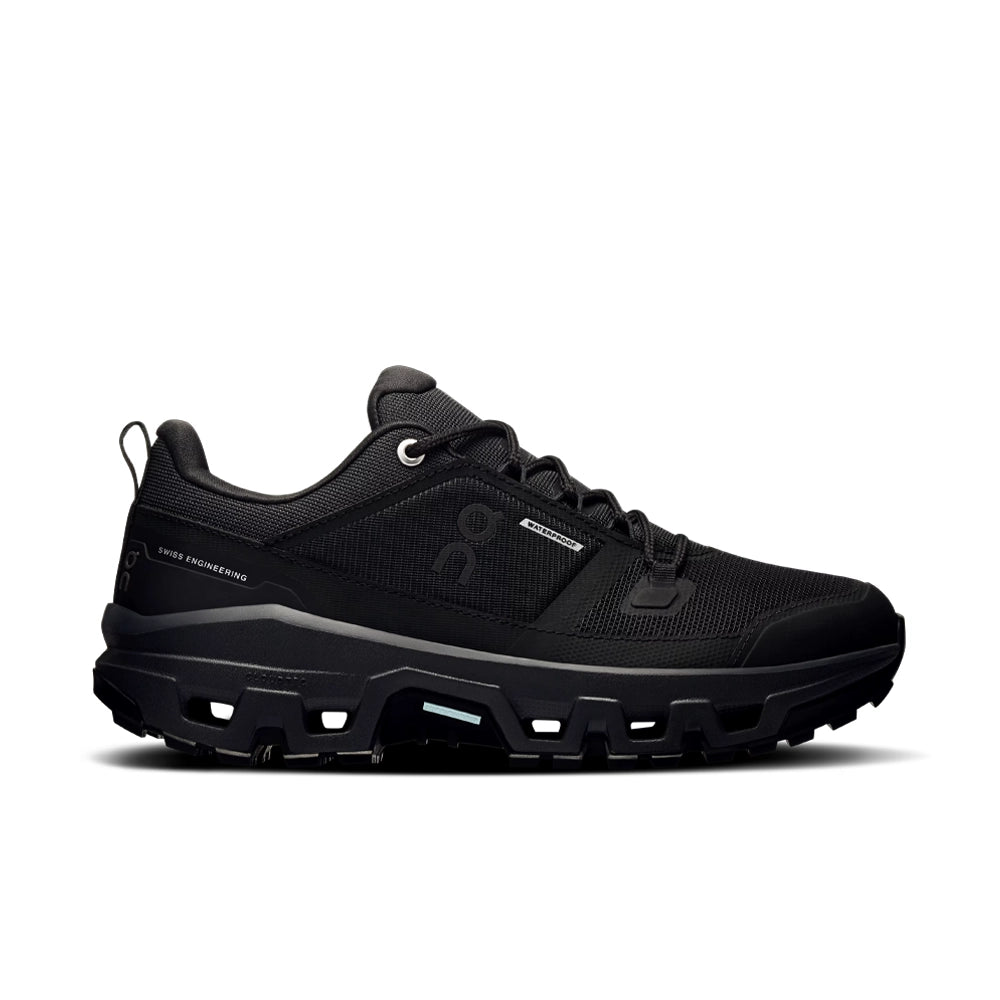 Side view of the women's On Cloudrock Low Waterproof in black, showing the lace-up upper and chunky lugged sole.