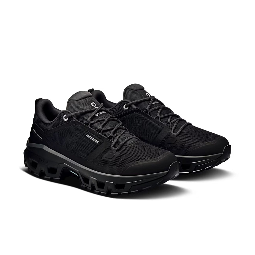 Pair of women's On Cloudrock Low Waterproof shoes in black, viewed from a front three-quarter angle.