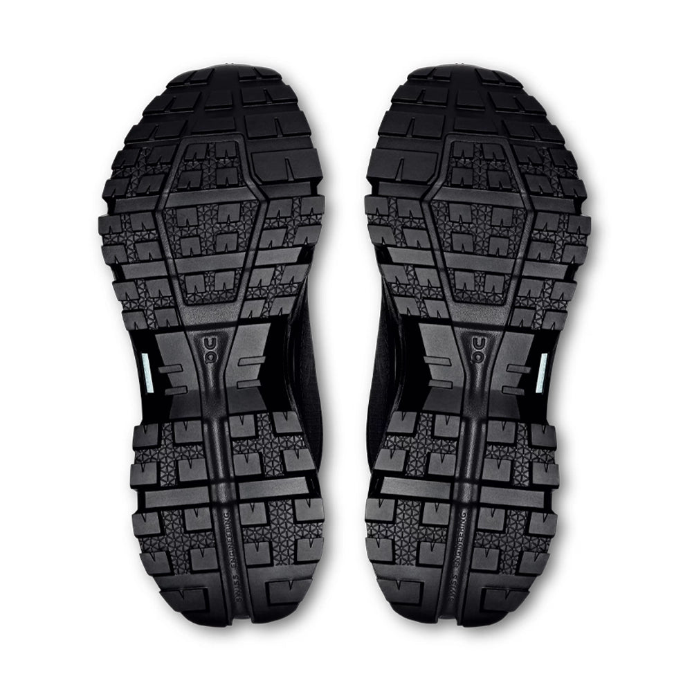 Outsoles of the black On Cloudrock Low Waterproof shoes, showing deep angular lugs and textured tread.