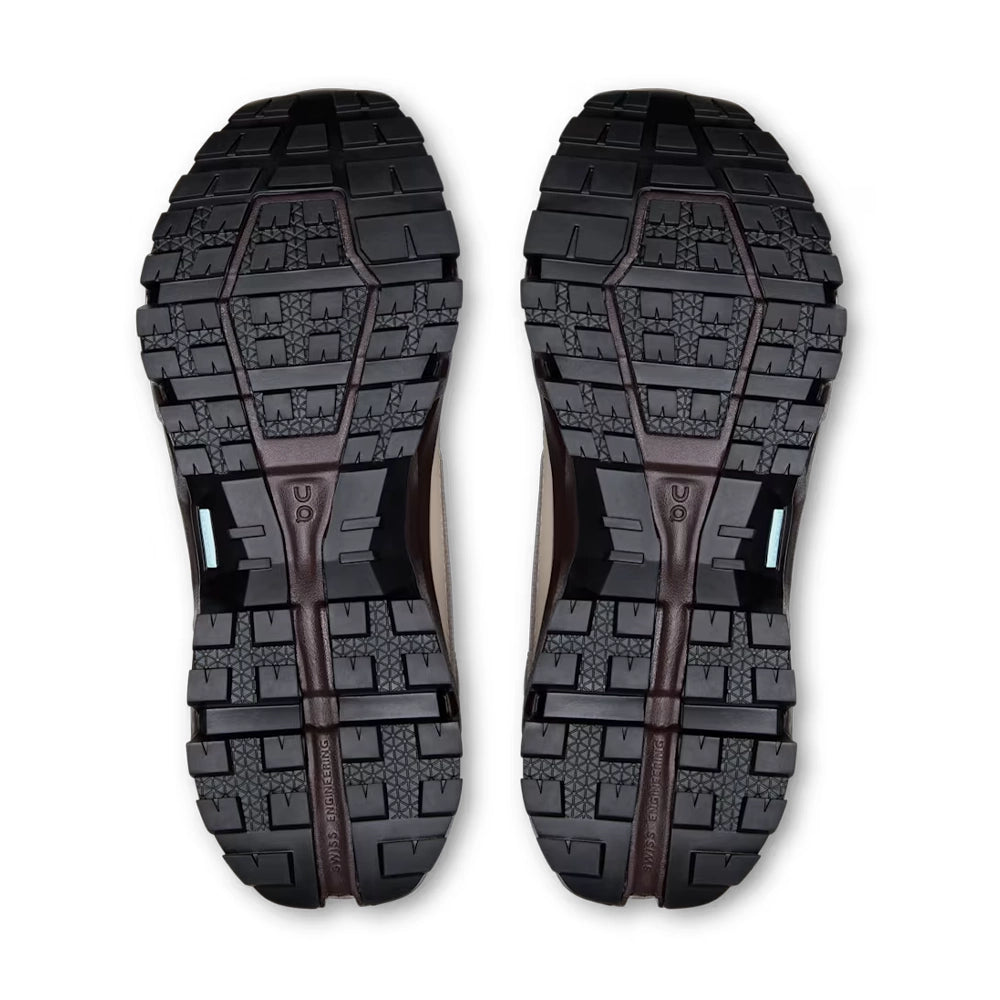 Bottom view of On Cloudrock Low Waterproof shoes showing black lugged outsoles and dark brown central grooves.