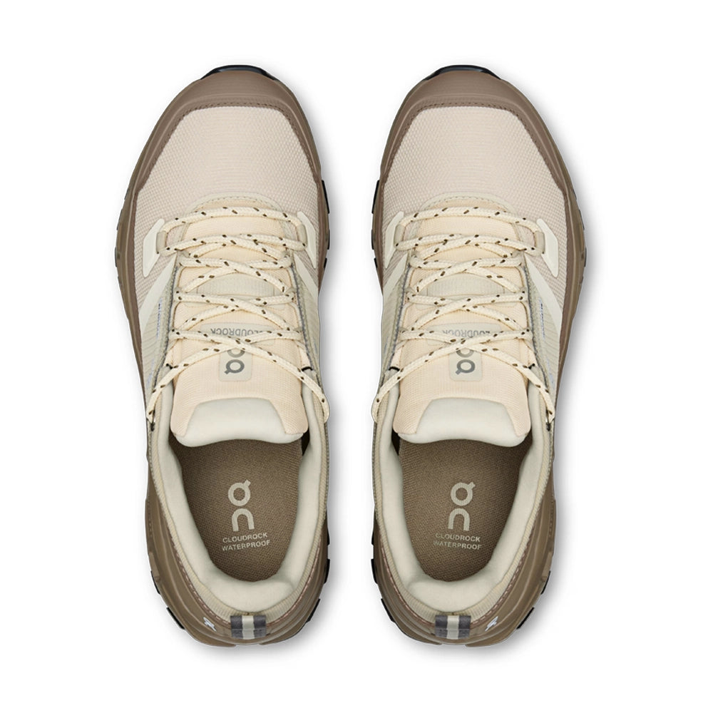 Top view of On women's Cloudrock Low Waterproof shoes in Grain Soba, showing cream lace-up uppers and padded collars.