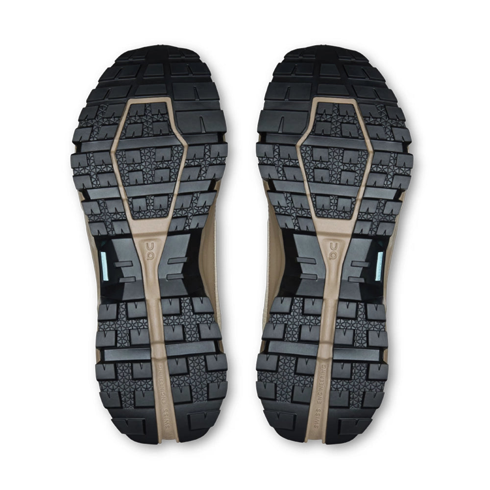 Bottom view of On women's Cloudrock Low Waterproof shoes, showing black lugged outsoles with grayish-brown channels