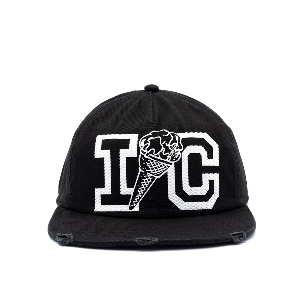 A black flat-brim baseball cap with distressed details on the brim, featuring a white embroidered graphic of the letters 'I' and 'C' with an ice cream cone motif in the center.