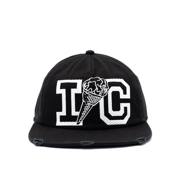 A black flat-brim baseball cap with distressed details on the brim, featuring a white embroidered graphic of the letters 'I' and 'C' with an ice cream cone motif in the center.
