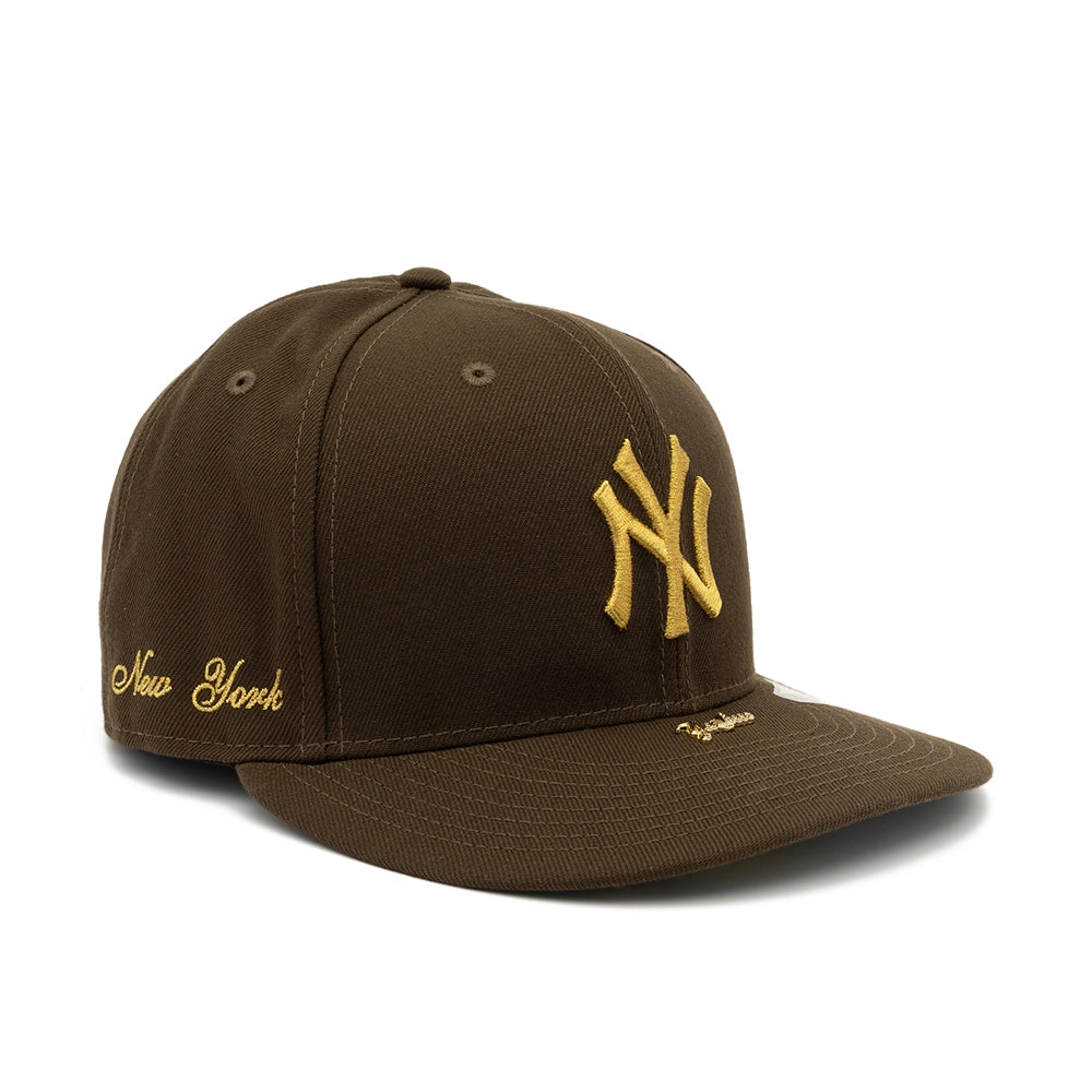 Angled view of walnut brown Yankees fitted cap with gold NY logo, New York script and Yankees visor pin.
