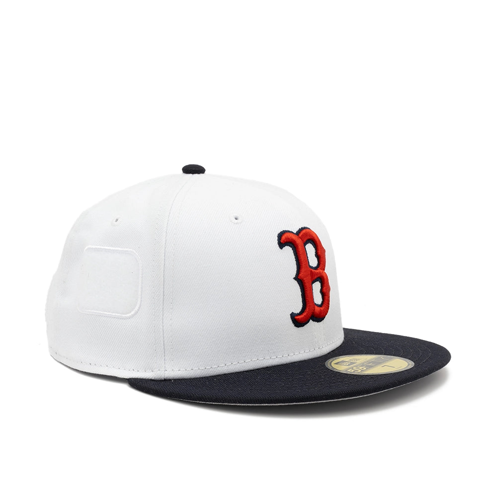 Angled view of the white Boston Red Sox fitted cap showing the red B logo and a white rectangular side patch panel.