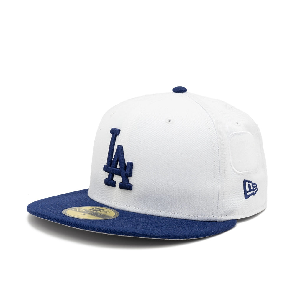 Angled view of the white Dodgers 59FIFTY cap with a navy LA logo, navy brim, and embroidered New Era flag.