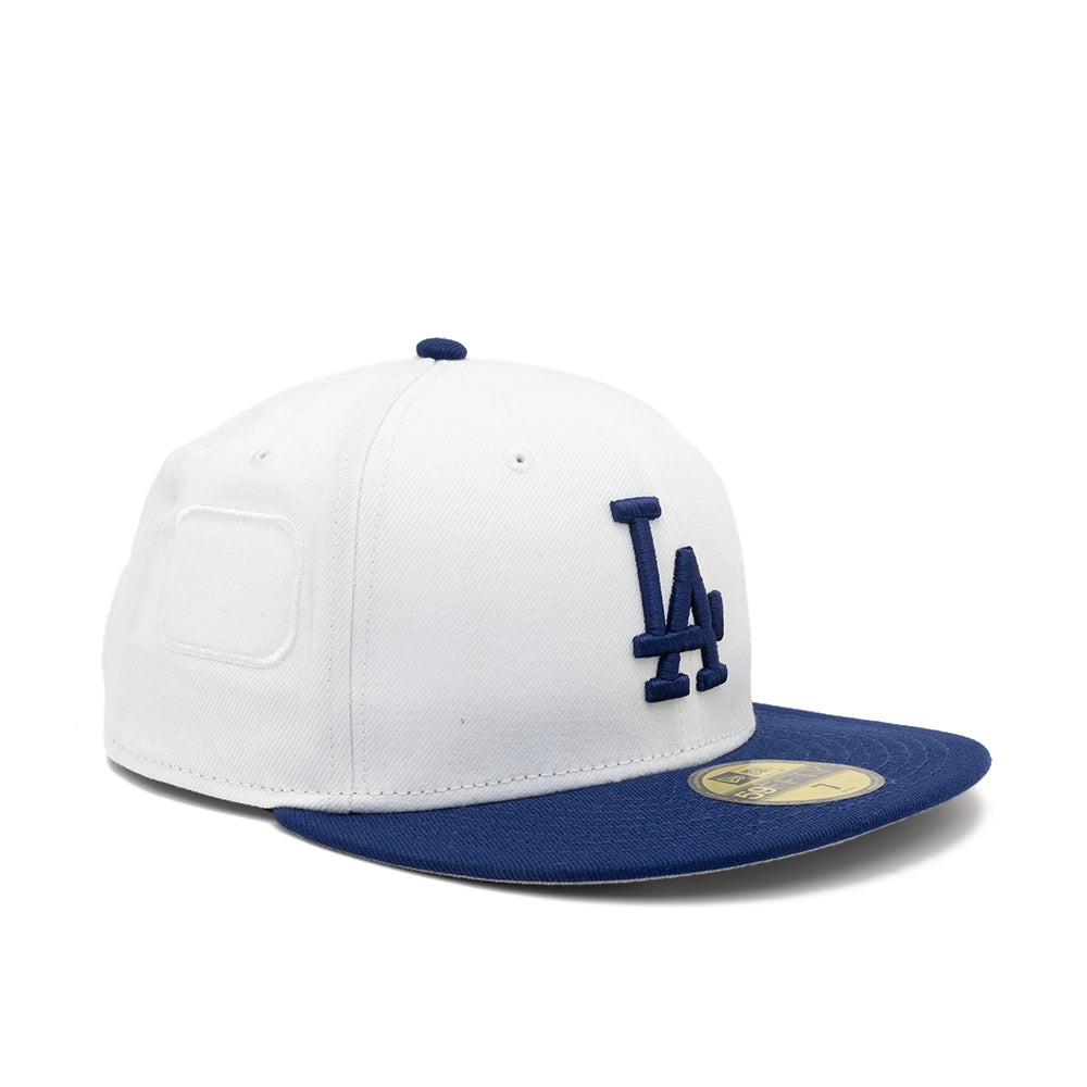 Angled view of the white Dodgers fitted cap showing the raised navy LA logo and white side patch panel.