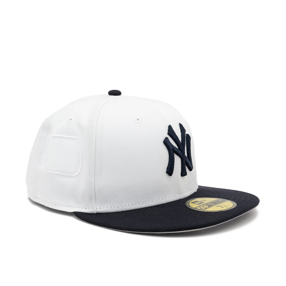 Opposite front angled view of the white Yankees fitted cap with raised navy NY embroidery and a navy brim.