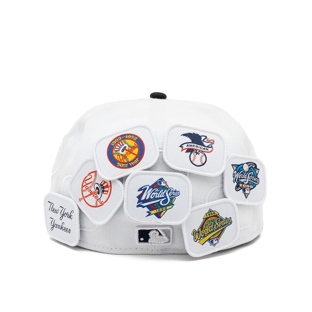 Rear view of the white Yankees fitted cap displaying seven patches with team logos and World Series designs.
