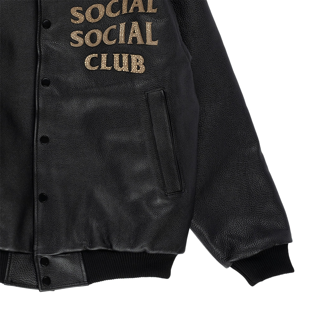 Close-up of black leather bomber jacket showing welt pocket, snap closure, ribbed cuff and hem.