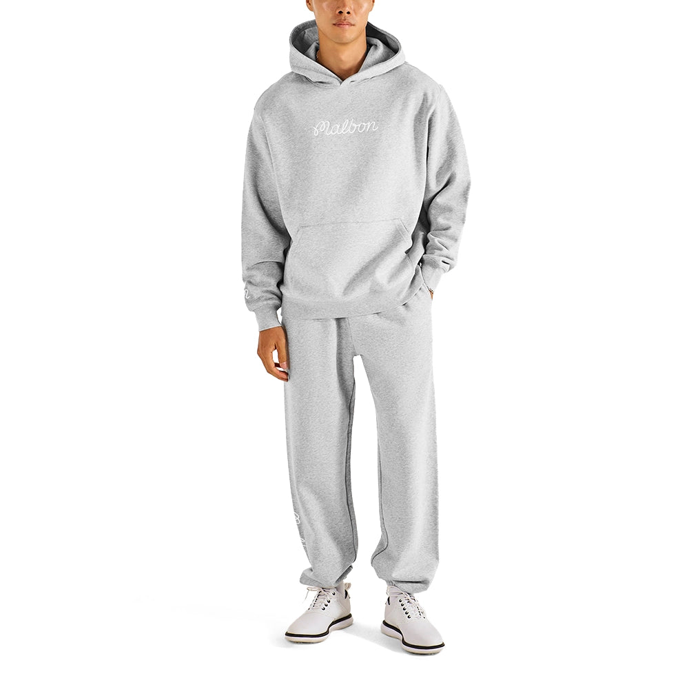 A model wearing a light gray heathered hoodie and matching sweatpants set, featuring a white script logo on the chest that reads 'Malbon'. The model is also wearing white sneakers, set against a plain white background.