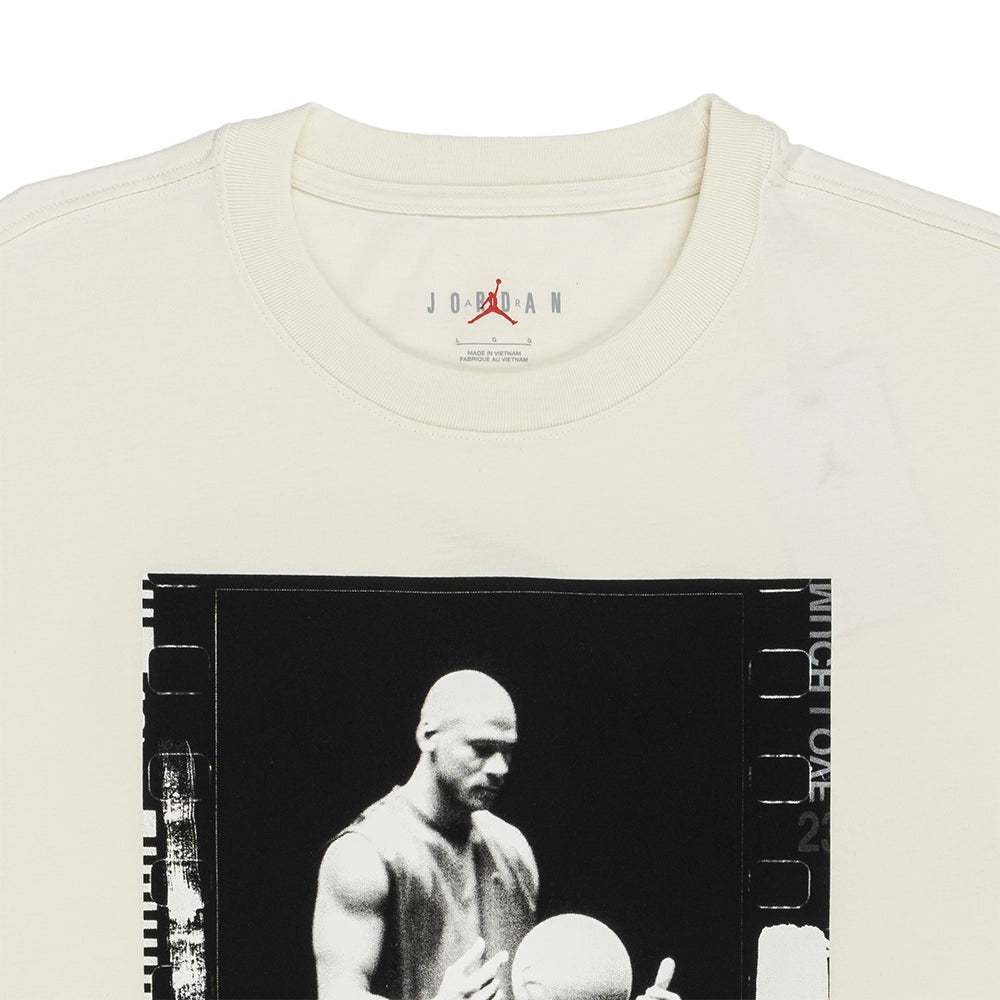 An off-white crewneck t-shirt featuring a large black-and-white graphic print of Michael Jordan holding a basketball, with a film-strip border design. The inside collar displays the Jordan brand logo.