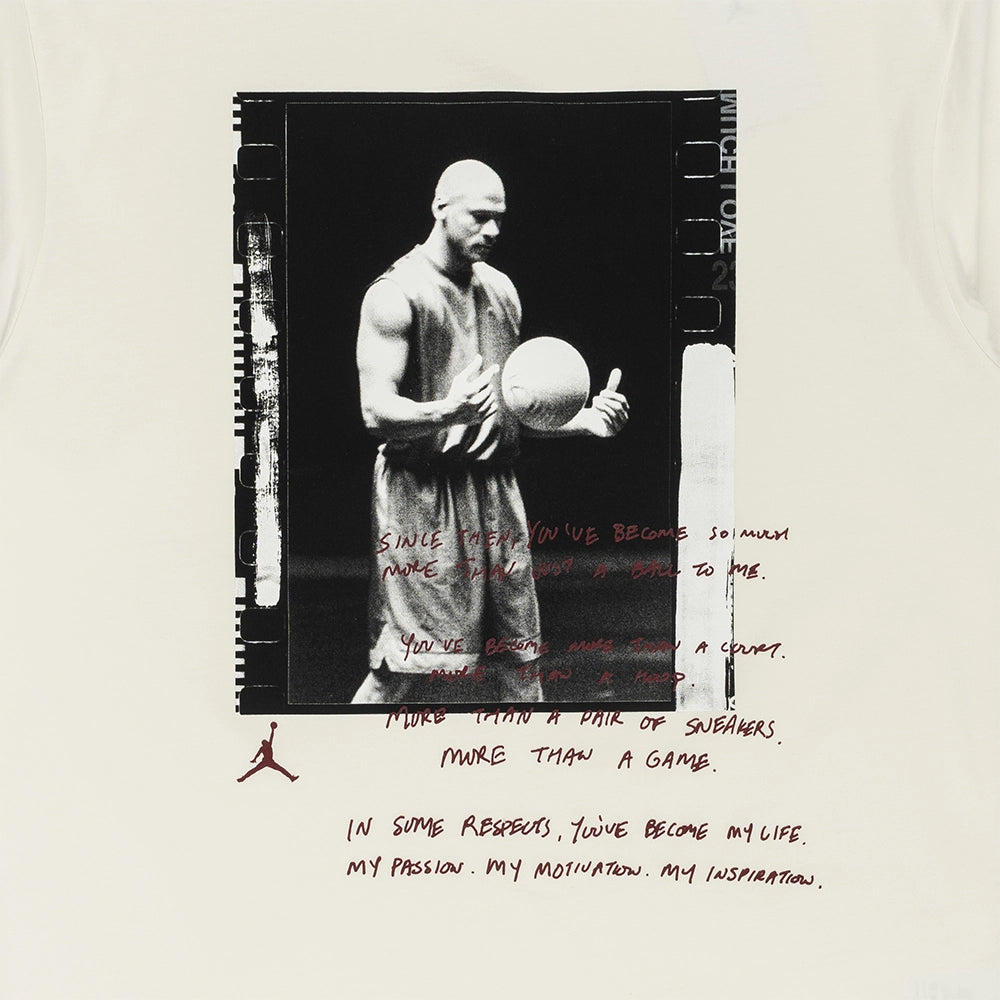 A white t-shirt featuring a graphic print of a black-and-white basketball player with handwritten red text and a small red Jordan logo, displayed flat against a white background.