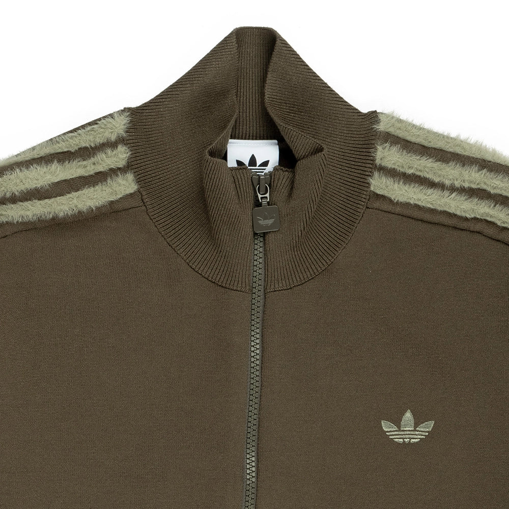 Close-up of adidas Firebird track top showing ribbed high collar, zipper, logo and textured shoulder stripes.