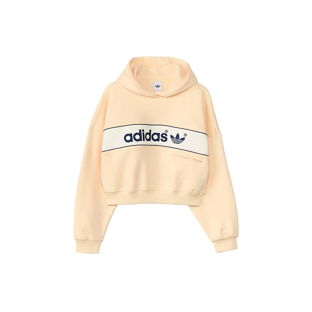Front view of adidas women's adiSignature NY hoodie in Warm Vanilla with navy chest branding and ribbed cuffs.