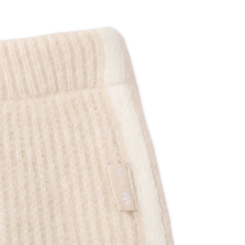 Close-up of the ribbed waistband and small side tab on adidas x Jennie Bliss cream knit pants.