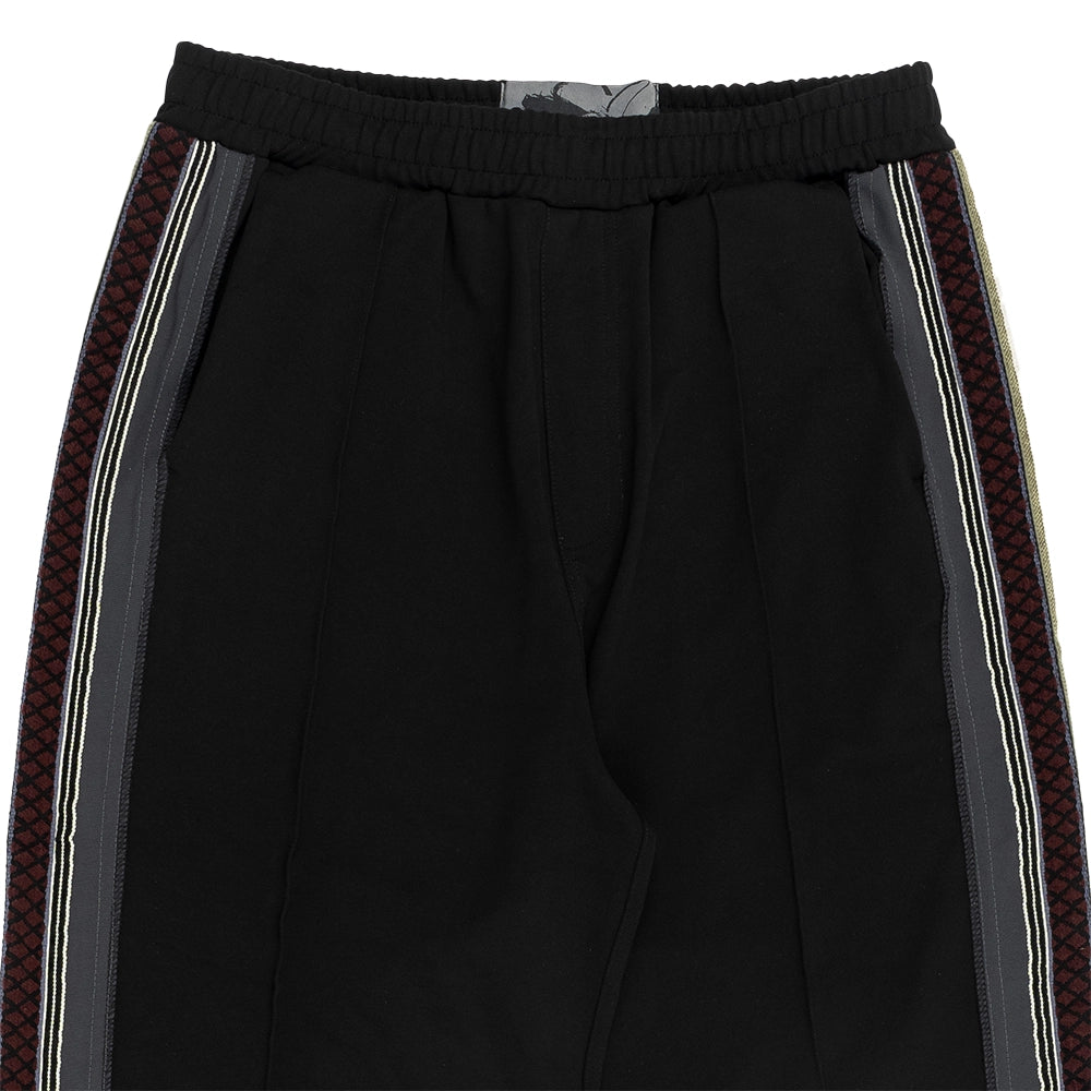 Black athletic pants featuring a textured geometric patterned stripe down the side, bordered by thin white and gray stripes, with a ribbed elastic waistband.