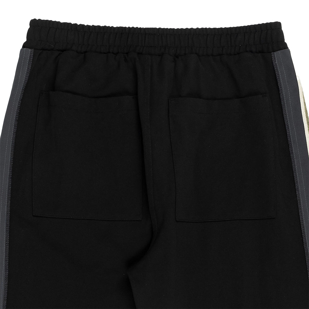 Close-up of the back of black athletic pants featuring two large patch pockets and dark gray side stripes running down the sides.