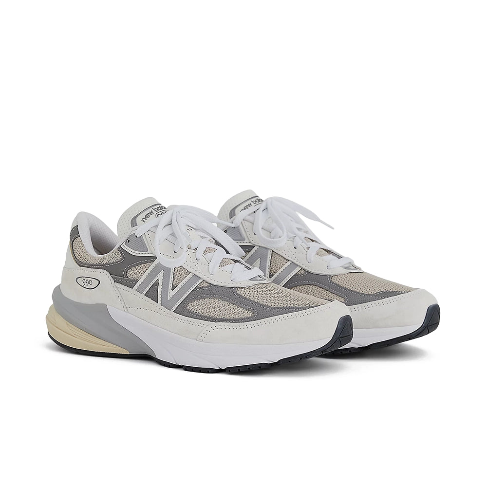 A pair of New Balance sneakers in a light gray and white colorway, featuring mesh panels, suede overlays, white laces, and a thick white and gray midsole with a beige heel accent, set against a plain white background.