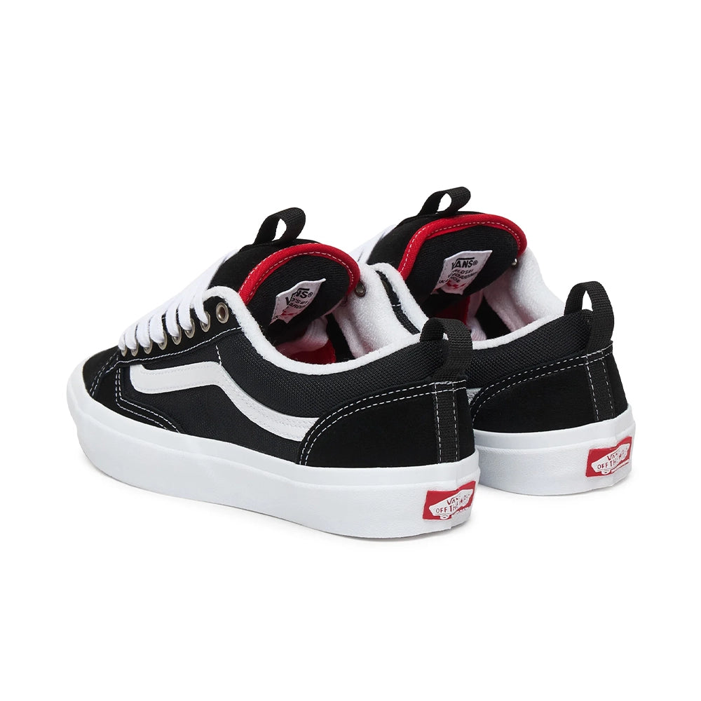 A pair of Vans Old Skool sneakers in black canvas with white rubber soles, white laces, and red accents on the collar lining and heel tab, shown against a plain white background.