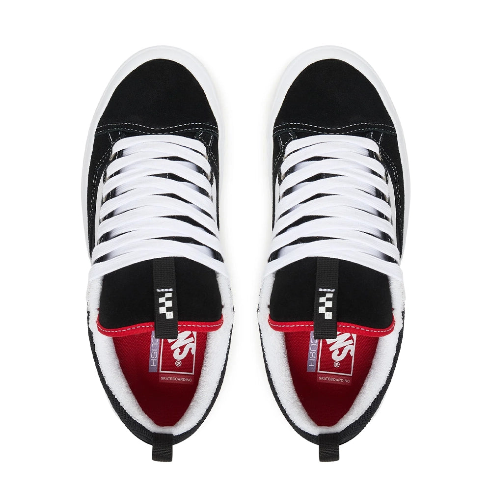 A pair of Vans skateboard shoes in black and white with a red interior lining, shown from a top-down view on a white background.