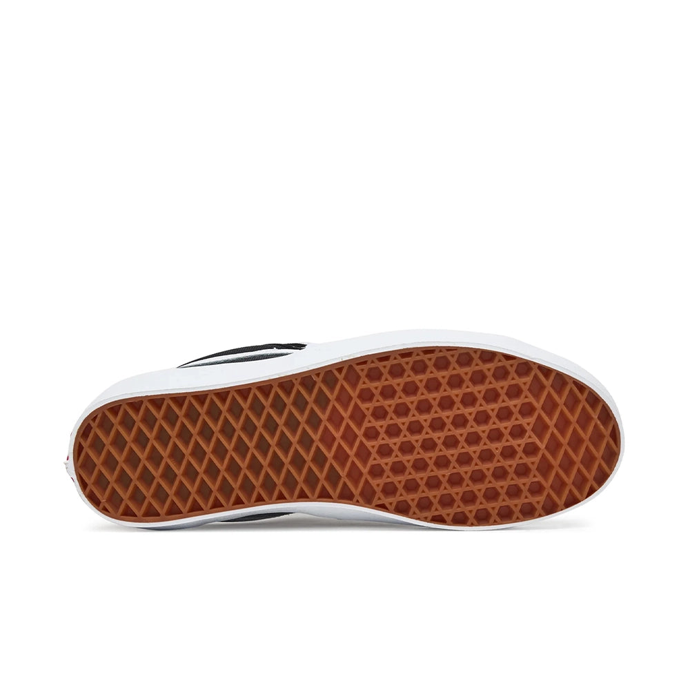 The bottom sole of a Vans slip-on shoe, showing a brown waffle-patterned rubber outsole and a white rubber toe bumper, on a white background.
